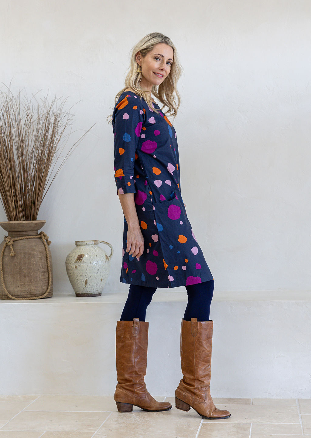Model standing sideways wears 3/4 sleeved cotton dress paired with brown boots