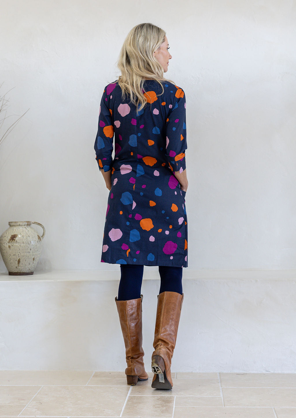 Model standing backwards wears 3/4 sleeved cotton dress paired with brown boots