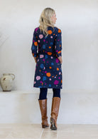 Model standing backwards wears 3/4 sleeved cotton dress paired with brown boots