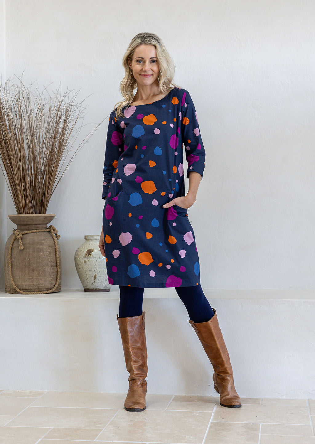 Model standing with one hand in pocket wearing 100% cotton dress in bold and colourful printed dress.