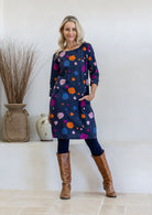 Model standing with one hand in pocket wearing 100% cotton dress in bold and colourful printed dress.
