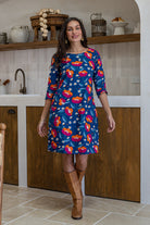 A woman wearing a 100% cotton knee-length dress in navy based floral print paired with brown boots.