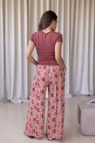 Model stands backwards wearing high waisted, relaxed fit cotton pants with drawstring and a hand in pocket. 
