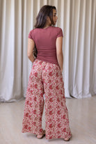 Model stands backwards wearing high waisted, relaxed fit cotton pants with drawstring and a hand in pocket. 