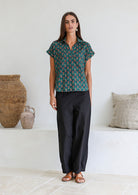 Woman poses in relaxed fit cotton short sleeve top with rolled cuffs sleeves, collar and V neckline.