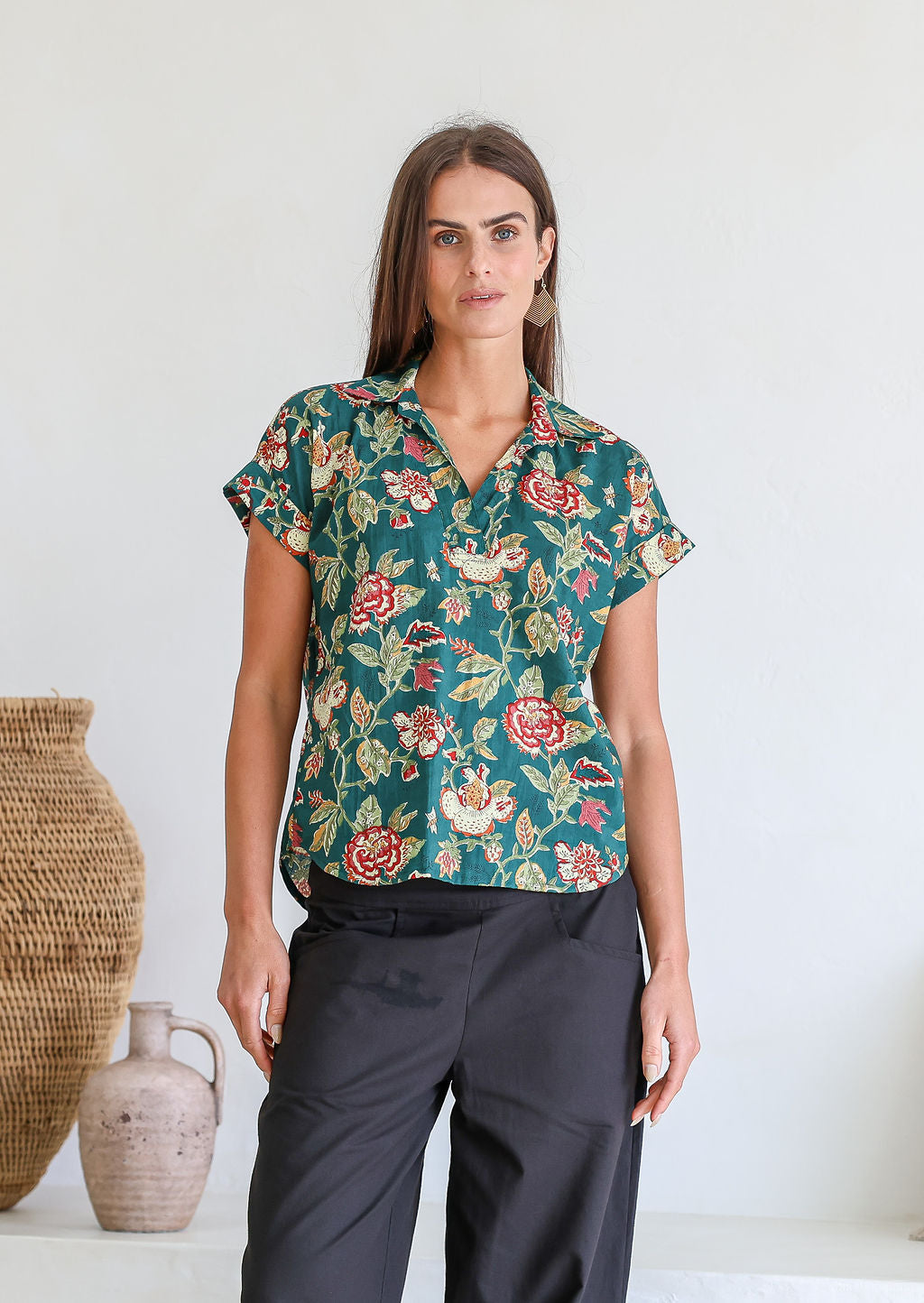 Woman poses in relaxed fit cotton short sleeve top with rolled cuffs sleeves, collar and V neckline.
