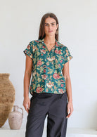 Woman poses in relaxed fit cotton short sleeve top with rolled cuffs sleeves, collar and V neckline.
