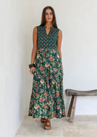 Model wears bottle green based floral cotton dress with pockets, 3/4 sleeves, V neck and mandarin collar.