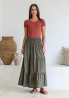 Model is wearing 100% cotton tiered maxi skirt in olive green shade with wide elasticated waistband.