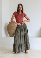 woman wearing a simple pink top and 100% cotton maxi skirt in olive green shade.