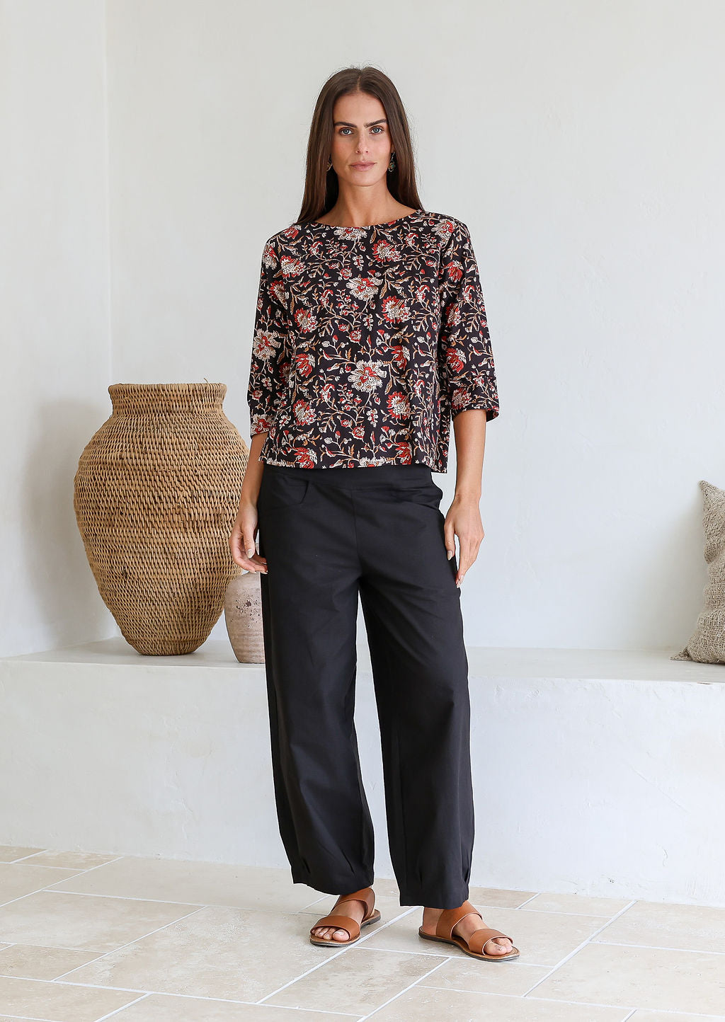 Model wears relaxed fit cotton top with 3/4 sleeves and round neckline in black based Indian traditional print