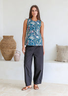 Woman wearing a sleeveless retro floral 100% cotton top with round neckline standing in a room with decorative vases.