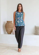 Woman standing in front of white wall wears 100% cotton sleeveless floral print top with keyhole button closure at the back