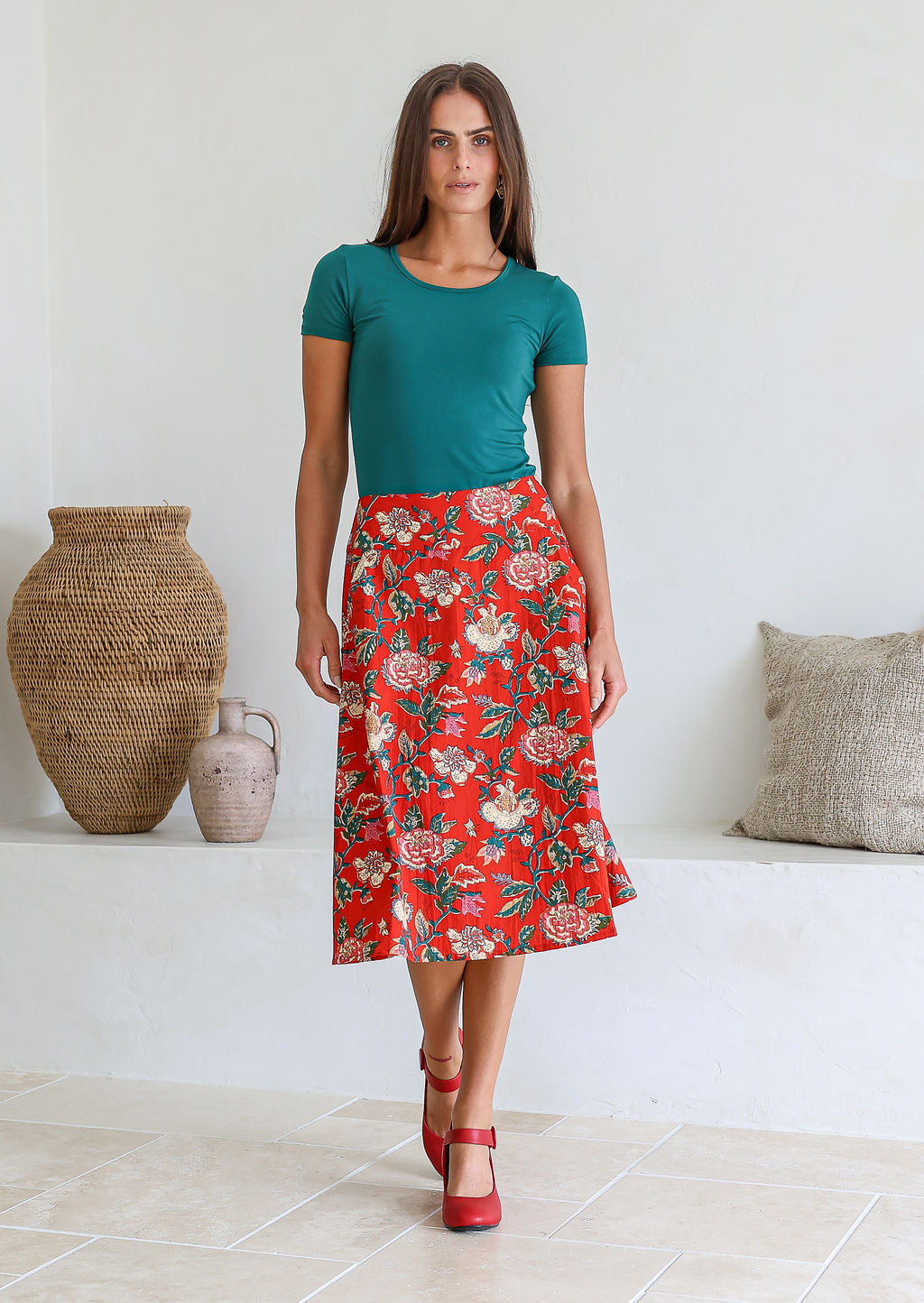 Model wearing 100% cotton knee length A-line skirt with side zipper and pockets in red based floral print