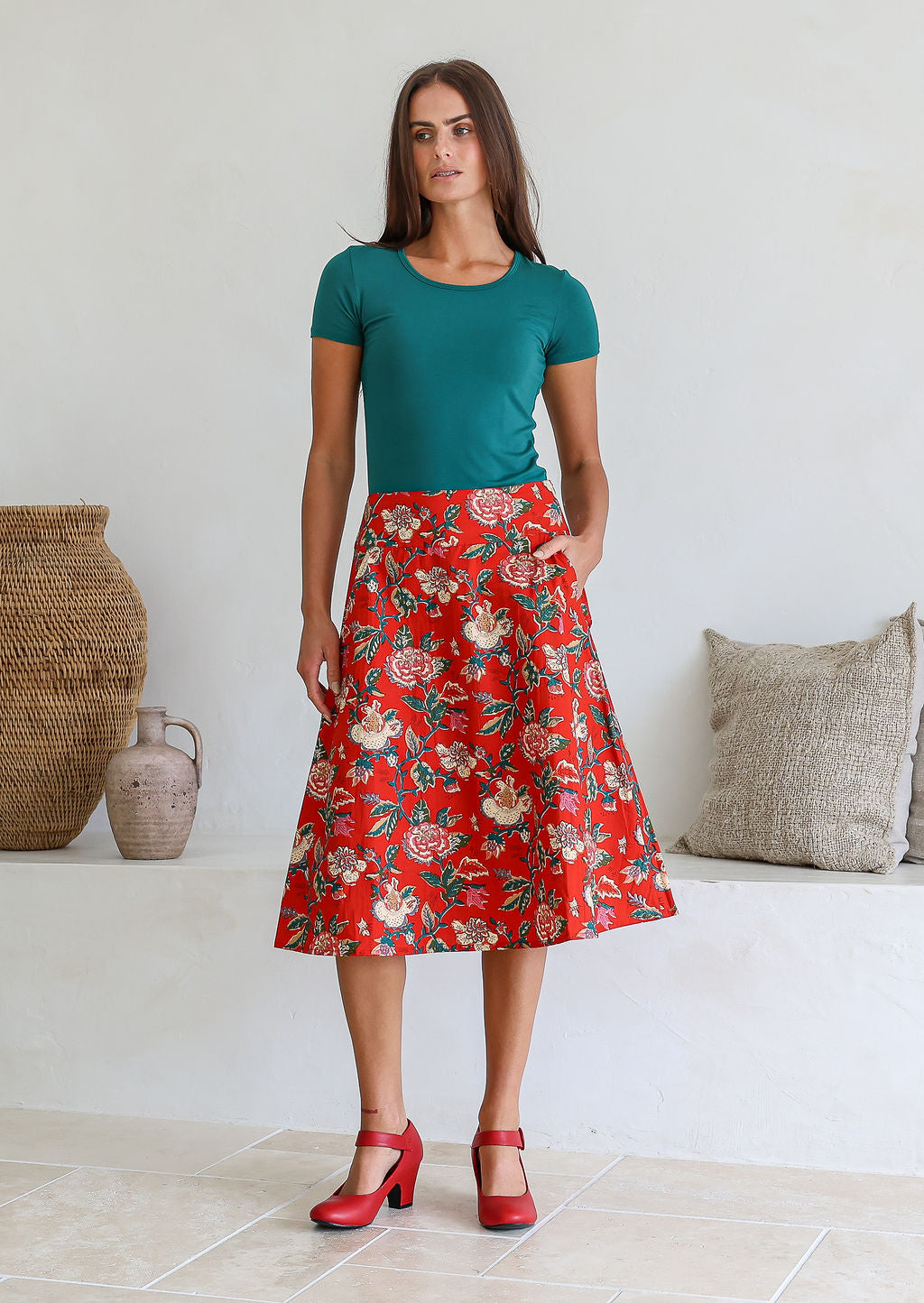 Woman is posing with one hand in pocket wearing a 100% cotton red a-line skirt.
