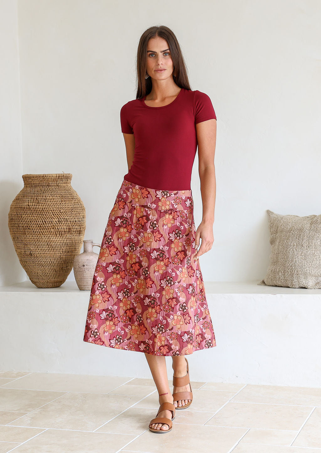 Woman is posing wearing a 100% cotton warm toned a-line skirt paired with a simple maroon top.