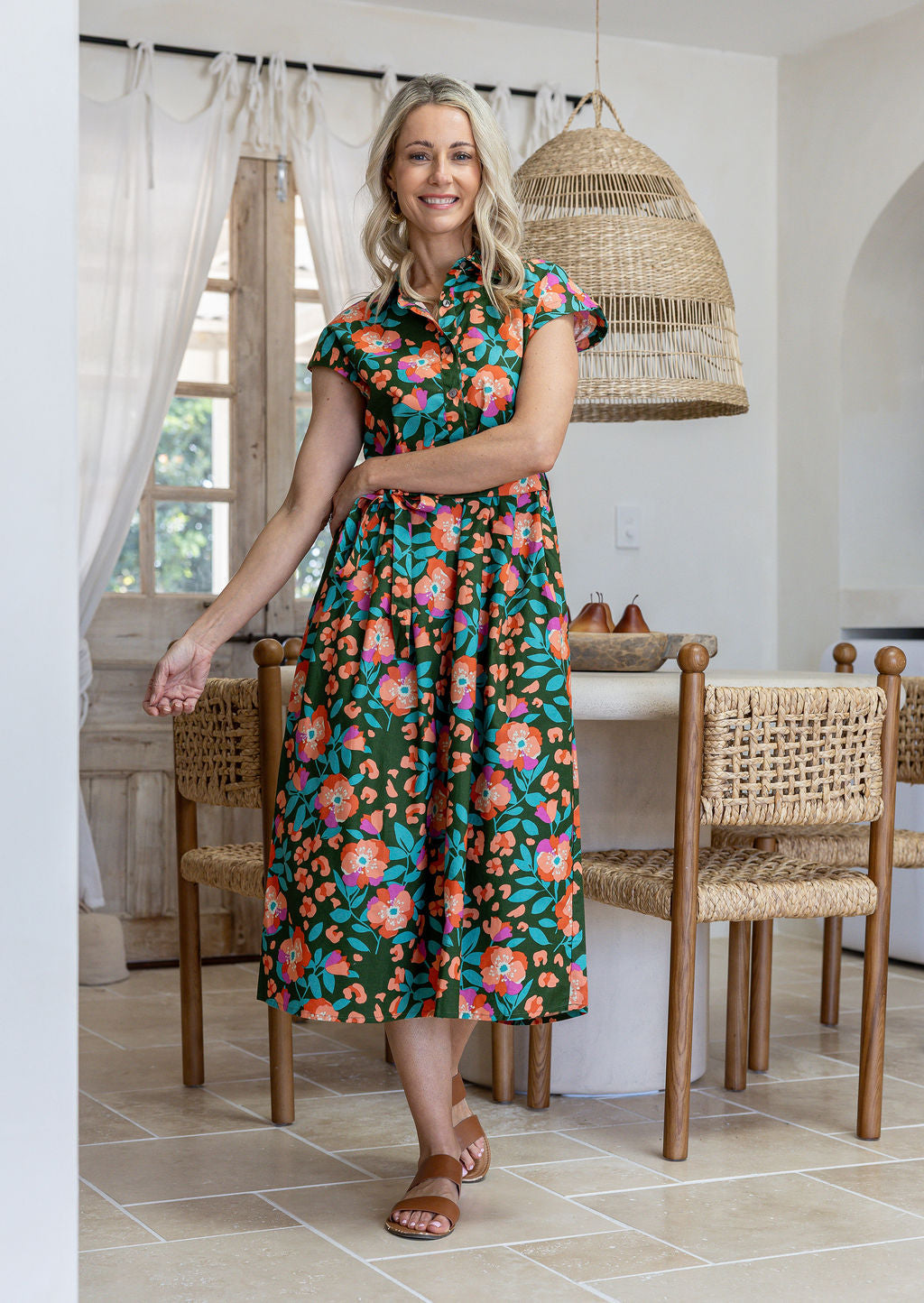 Model wearing a 100% cotton shirt style dress in olive green based floral print with removable waist tie and pockets
