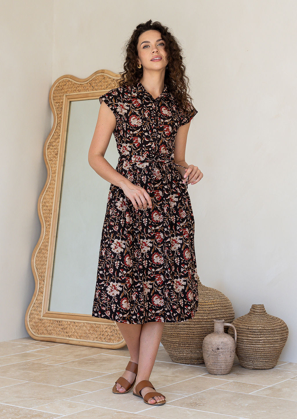 Woman wearing a shirt style cotton midi length dress with buttoned bodice, pockets, collar and cap sleeves