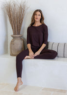 Woman sitting down wearing dark brown stretch rayon jersey top and leggings in a light room