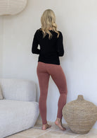 Woman standing backwards wearing a 100% rayon soft stretch jersey leggings in dusty pink colour. 