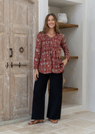 Woman wearing a red based cotton floral long sleeve relaxed fit blouse with a V-neckline