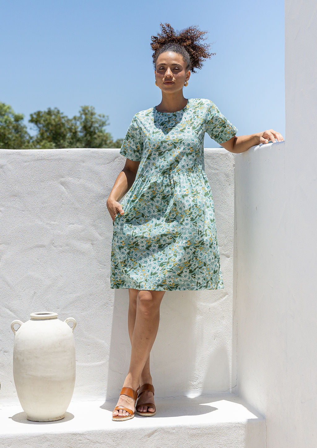Woman wearing a 100% cotton relaxed fit dress with round neckline and short sleeves in sage green based floral print.