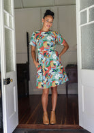 Woman wearing a relaxed fit, above knee length cotton dress with colourful floral print.