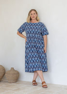 Woman wearing a 100% cotton relaxed fit dress in navy based floral print with round neckline. 
