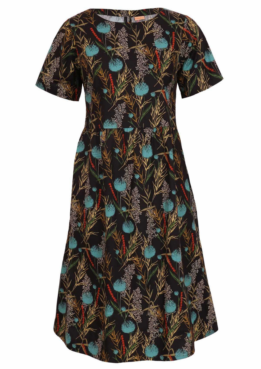 Model wears a 100% cotton floral black base dress with pops of blue and red. This loose fitting, below knee length dress has short sleeves, a high round neckline and pockets.