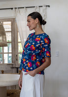 Woman standing sideways wearing a relaxed n fit royal blue based printed cotton top. 