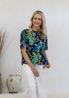 Woman wearing a navy based floral print relaxed fit cotton top with short sleeves and high neckline