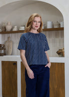 Woman wearing a navy striped cotton loose fit short sleeved top and pants with hand in pocket