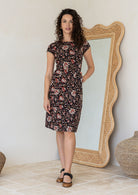 Model wears a simple knee length cotton dress with round neckline, short cap sleeves, pockets and a slight A-line skirt.