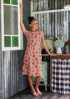 Model wears a knee length A line dress with cap sleeves in cream based floral print