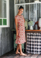 Model wears a knee length A line dress with cap sleeves in cream based floral print