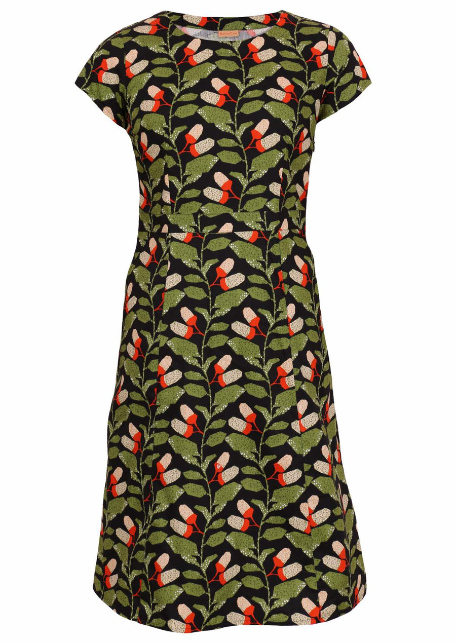 Model wears Nina Dress Oak green and black botanical print cotton retro dress with round neckline, cap sleeves, A-line skirt and pockets | Karma East Australia