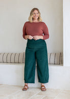 Woman wearing a cotton corduroy wide-leg dark green pants. 