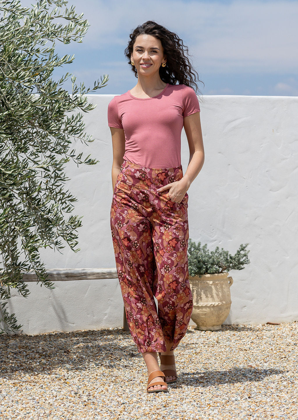 Woman standing in a wide leg cotton pants with high waste, pockets and pleated ankles 