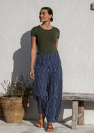 Woman wearing cotton wide leg pants in navy based white striped print with pockets paired with basic top 