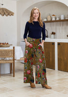 Woman wearing a basic top with green based multi-colour floral velvet wide leg pants with pockets and a side zip