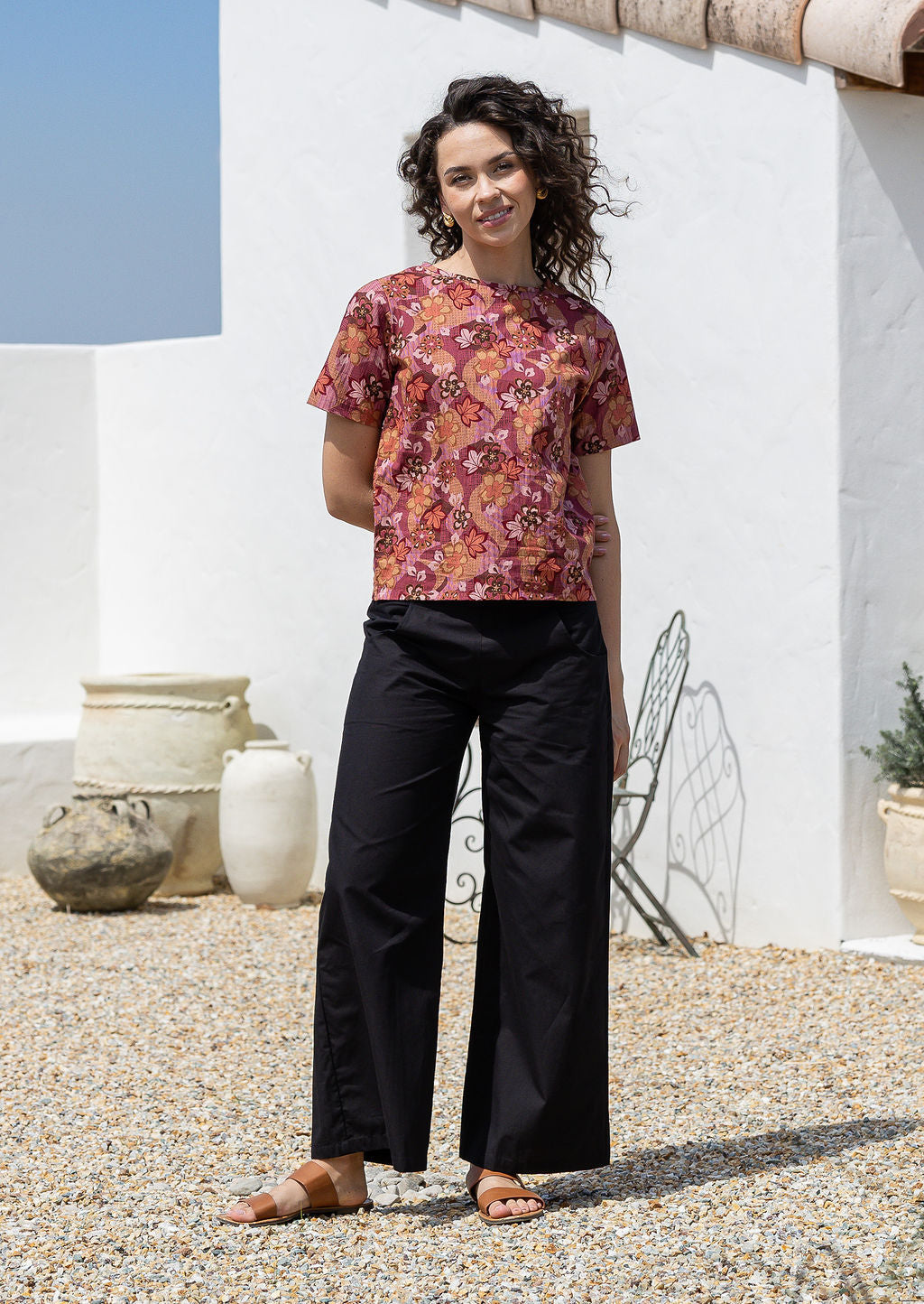 Woman wearing a 100% cotton loose fitting black top with short sleeves, round neckline and button back closure