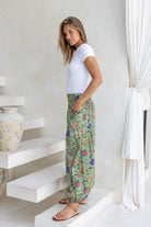 Side pose of model wearing a floral cotton pants with elastic ankles and waist.