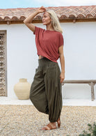 Woman poses in 100% cotton crinkle-harem pants in olive green shade with flat front waistband and shirred back waist