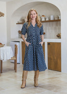 Woman wearing a navy blue floral cotton button through dress with both hands in hidden side pocket