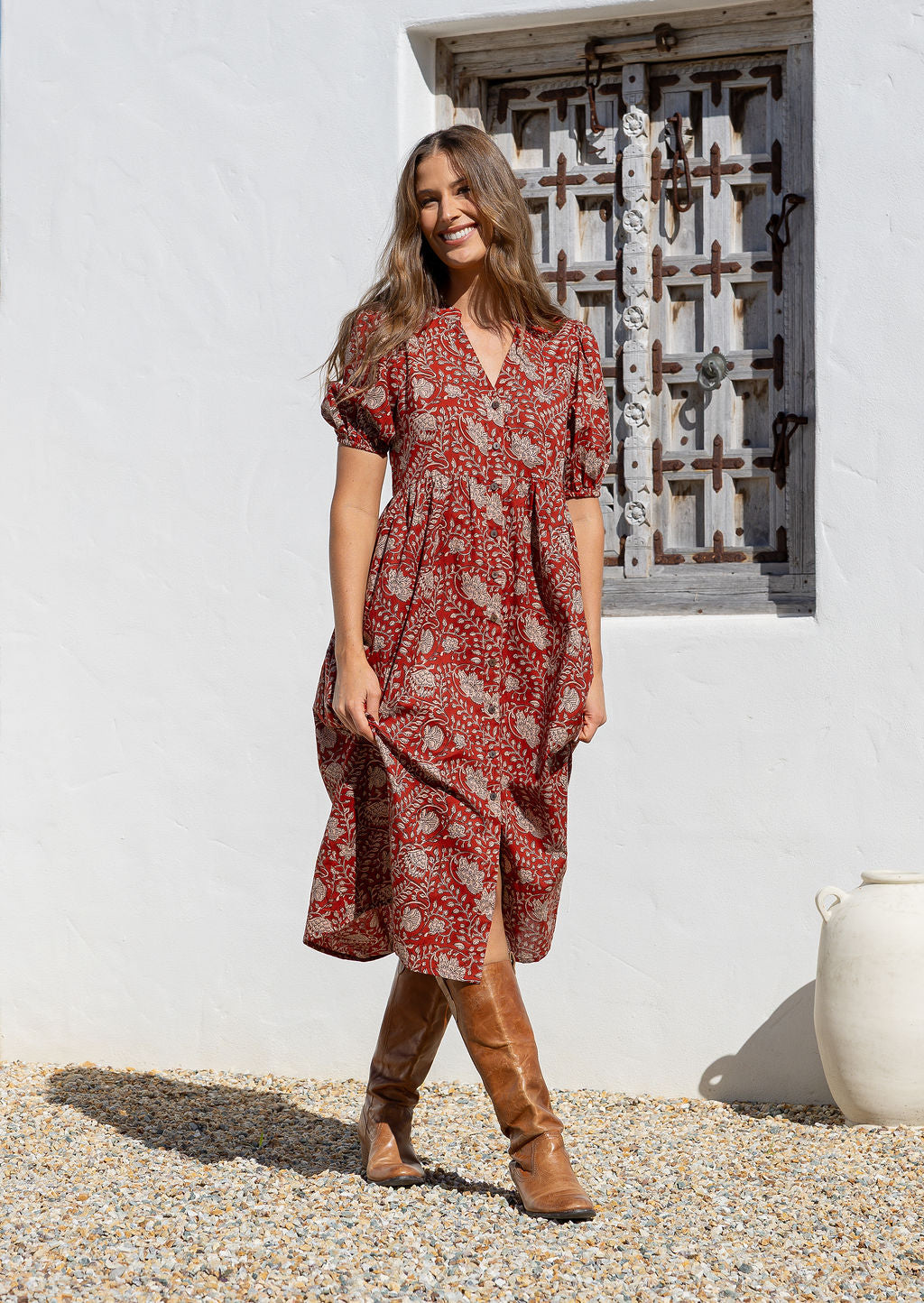 Woman in a red floral cotton button through dress with elbow length puffy sleeves and a V-neckline. 