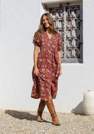 Woman in a red floral cotton button through dress with elbow length puffy sleeves and a V-neckline. 