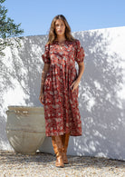Woman wearing a red floral cotton button through dress with one hand in hidden side pocket