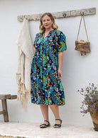 Woman in a floral dress standing against a white wall