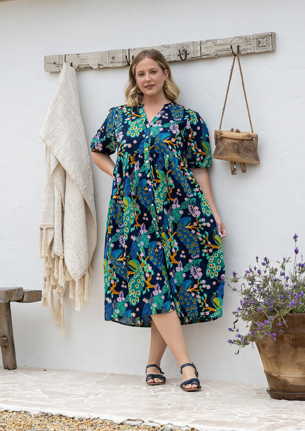 Woman wearing navy based colourful floral cotton button through dress with  hidden side pocket