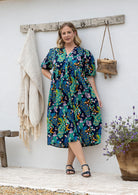 Woman wearing navy based colourful floral cotton button through dress with  hidden side pocket